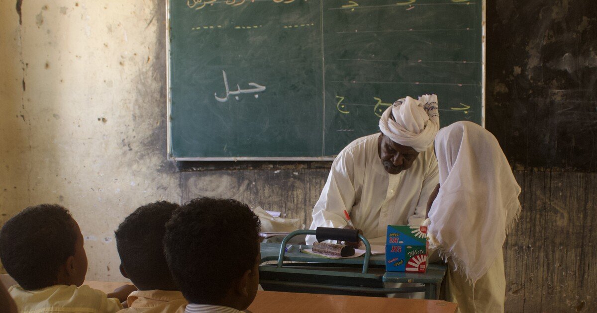معلم سوداني يجلس مع تلميذة أمام سبورة داخل فصل بمدرسة مساوي في شمال السودان